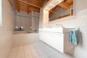 a white bathroom with a sink and a tub at Chalet Domaine de la Famille te Arbaz in Arbaz
