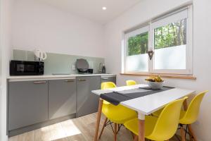 a kitchen with a table and yellow chairs at Domki Amare in Pobierowo