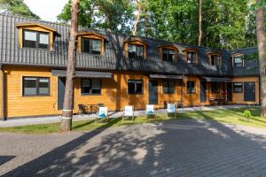 a wooden house with chairs in front of it at Domki Amare in Pobierowo