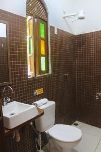 baño con aseo y lavabo y ventana en Hospedaria Flor de Caju, en Pipa