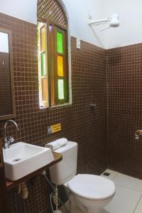a bathroom with a toilet and a sink and a window at Hospedaria Flor de Caju in Pipa