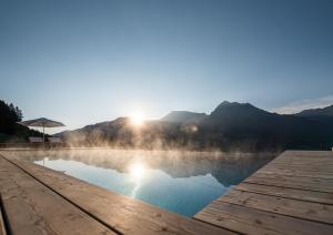 ein Wasserbecken mit der Sonne im Hintergrund in der Unterkunft Der Jägersberg in Fischen im Allgäu