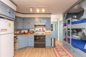 Alyeska Retreat C110 في جيردوود: مطبخ مع خزائن زرقاء وأسرّة بطابقين