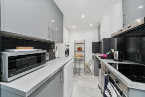 a white kitchen with a microwave and a counter at Cosy Apartment in the Heart of the City in London