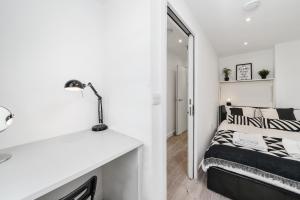 a white bedroom with a bed and a desk at Cosy Apartment in the Heart of the City in London