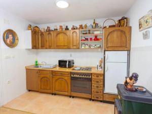 a kitchen with wooden cabinets and a white refrigerator at Villa in Tu epi with Private Swimming Pool in Tučepi
