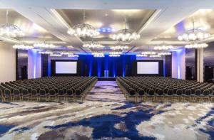 Habitación grande con sillas y un escenario con pantallas. en Hyatt Regency Rochester, en Rochester