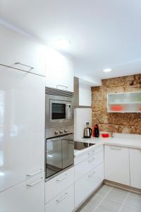 a kitchen with white cabinets and stainless steel appliances at Dúplex Camino de Santiago I, Rúa Real, Pontevedra in Pontevedra