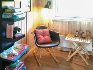 a black chair with a pink pillow sitting next to a table at 12 person holiday home in Idestrup in Marielyst