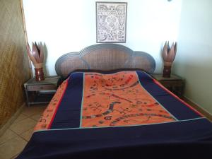 a bed with a blue and orange blanket on it at Hôtel Atiapiti in Opoa
