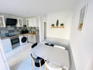 a white kitchen with a white table and chairs at 022 CHIC & COSY GRAND APPART DUPLEX 92m2 WIFI SMART TV NETFLIX in Saint-Étienne