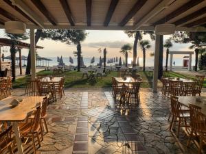 um restaurante com mesas e cadeiras e vista para o oceano em OCEANA Beach Hotel em Paralia Panteleimonos