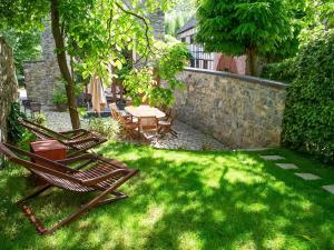un patio con sillas, una mesa y una pared de piedra en Charming house in Sint Jansrade with private pool and sauna, en Aubel