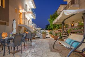 eine Terrasse mit Stühlen, Tischen und einem Sonnenschirm in der Unterkunft M&B boutique apartments in Nea Roda