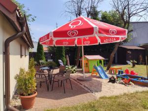 a red umbrella and chairs and a table and a playground at Letni Wiatr Willa Retro in Łeba