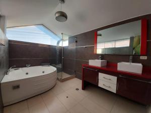 La salle de bains est pourvue d'une baignoire, de 2 lavabos et d'un miroir. dans l'établissement Apart Hotel Atenea, à Ilo