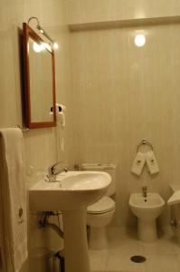 a bathroom with a sink and a toilet and a mirror at Hotel Paraiso in Oliveira do Bairro
