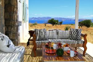 a couch and a table on a porch with a view of the ocean at Aegean Blue Houses in Mandrakia