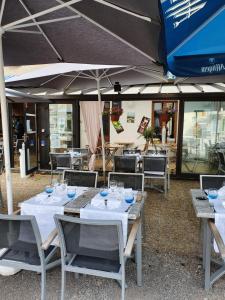 a group of tables and chairs under an umbrella at Hotel L'envie des mets in Lus-la-Croix-Haute