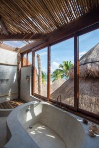 a bathroom with a large tub and a large window at Delek Tulum located at the party zone in Tulum