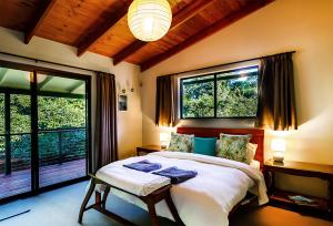 1 dormitorio con 1 cama grande y 2 ventanas en Bundara - Idyllic Getaway in the Mountains, en Mount Tamborine