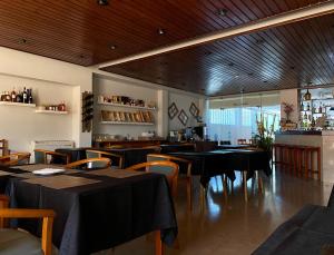 a restaurant with tables and chairs and a bar at Hotel Paraiso in Oliveira do Bairro