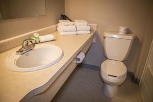 a bathroom with a toilet and a sink with towels at Bedrock Motel in Mayo Landing