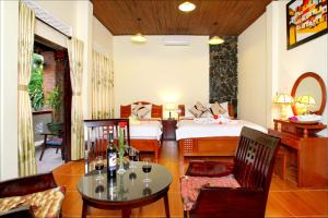 a room with two beds and a table and chairs at Bamboo Garden Homestay in Hoi An