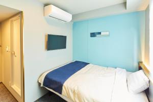 a bedroom with a bed and a tv on the wall at ICI HOTEL Tokyo Hatchobori in Tokyo