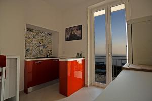 una cucina con armadi rossi e vista sull'oceano di Alma Cilento ad Ascea