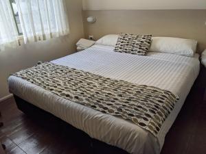 a bed with a white comforter and pillows at Wollongong Surf Leisure Resort in Wollongong