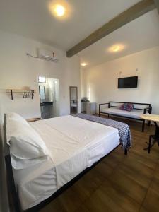 a bedroom with a large white bed and a table at Flor de Mandacaru Pousada in Boqueirão (1)