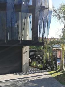 a house with a glass facade with palm trees at CBD Grampians studio in Nelson