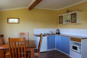 cocina con mesa, armarios azules, mesa y sillas en Blue Thistle Cottages, en Te Anau