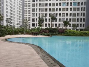 a swimming pool in front of two tall buildings at Relax 3BR Apartment at M-Town Residence By Travelio in Tangerang
