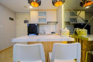 a kitchen with two white chairs and a counter at Relax 3BR Apartment at M-Town Residence By Travelio in Tangerang