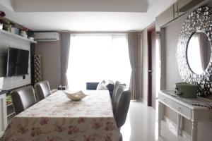 バンドンにあるCozy 2BR Apartment at Tamansari Tera Residence near BIP By Travelioのテーブルと椅子とテレビのあるダイニングルーム