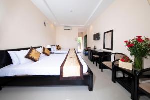 a bedroom with a large bed and a table at Hon Rom Central Beach Resort in Mui Ne