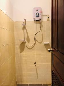 uma casa de banho com um chuveiro e um secador de cabelo na parede em HideSeek Hostel Vientiane Thai embassy em Vientiane