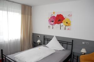 1 dormitorio con 1 cama y una pintura en la pared en Parkhotel Krone, en Emmendingen