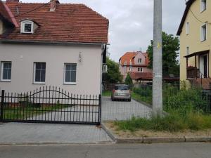 a white house with a gate and a car on a street at zacisze in Jelenia Góra