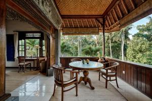 una sala da pranzo con tavolo e sedie su un portico di Alam Shanti Ubud ad Ubud