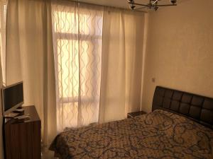 a bedroom with a bed and a window with curtains at Guest House Oliva in Adler