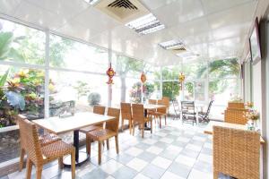 un restaurante con mesas, sillas y ventanas grandes en Daniel Motel en Xinying