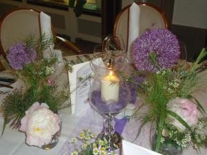 - une table avec une bougie et des fleurs violettes et blanches dans l'établissement Parkhotel Krone, à Emmendingen