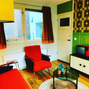 a living room with a red chair and a tv at Retro-huisje GoedFout in Olst