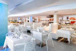 un restaurante con mesas blancas y sillas blancas en FERGUS Style Cala Blanca Suites, en Santa Ponsa