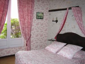 - une chambre avec un lit doté de rideaux roses et d'une fenêtre dans l'établissement La Ferme des 3 Maillets, à Avaray