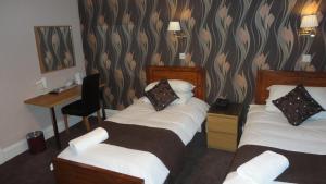 a hotel room with two beds and a desk at Sandyford Lodge - Hotel West in Glasgow