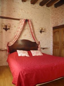 a bedroom with a red bed with a red blanket at La Ferme des 3 Maillets in Avaray